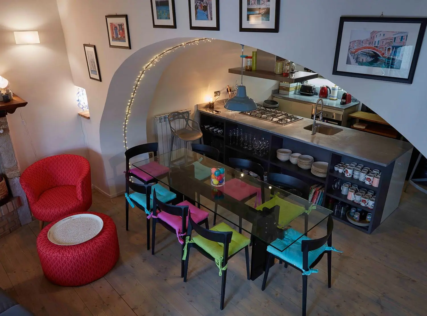 Dining table with eight coloured chairs beside the open kitchen