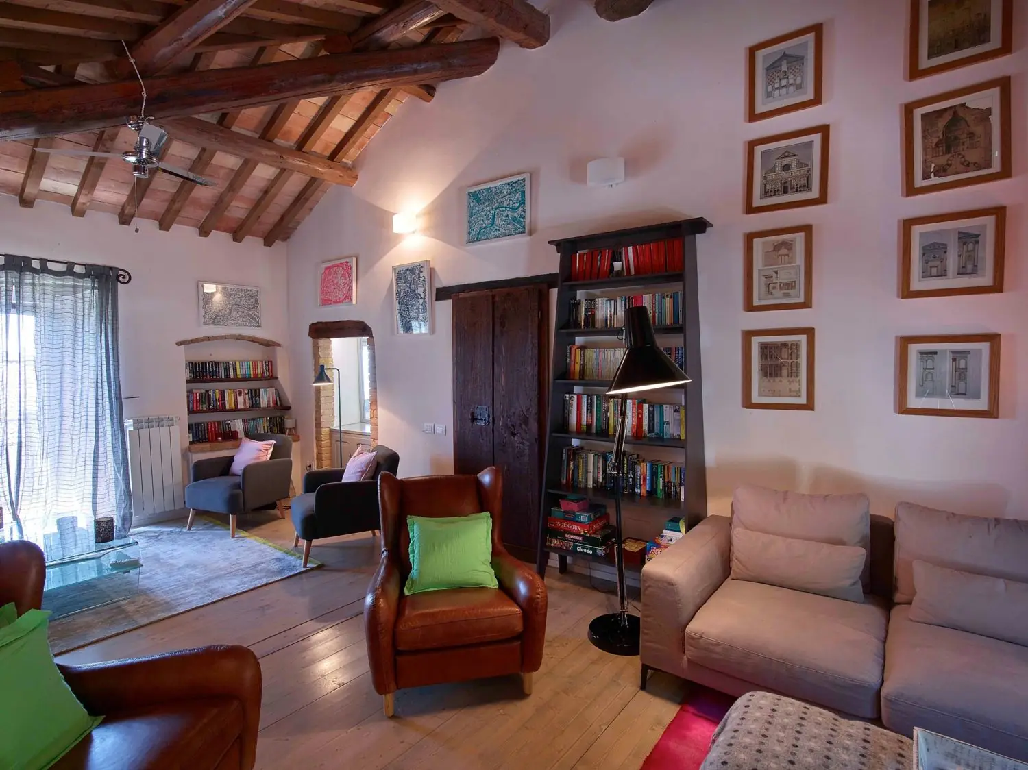 Living room with bookcase, sofas and an arched wooden door