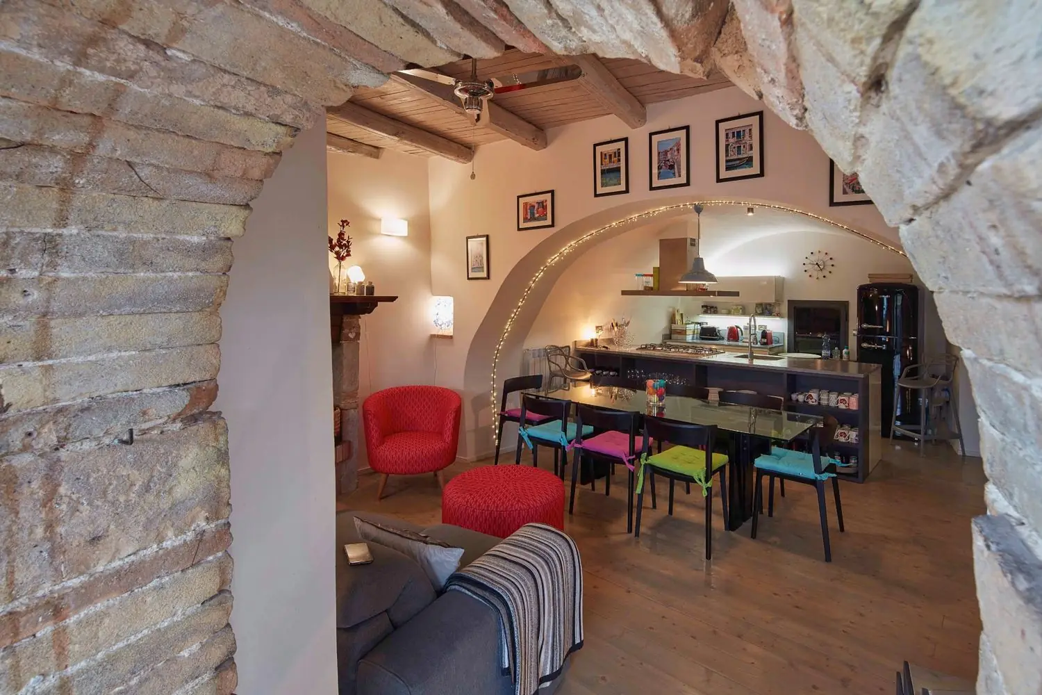 View through a rough stone arch into the dining room and kitchen